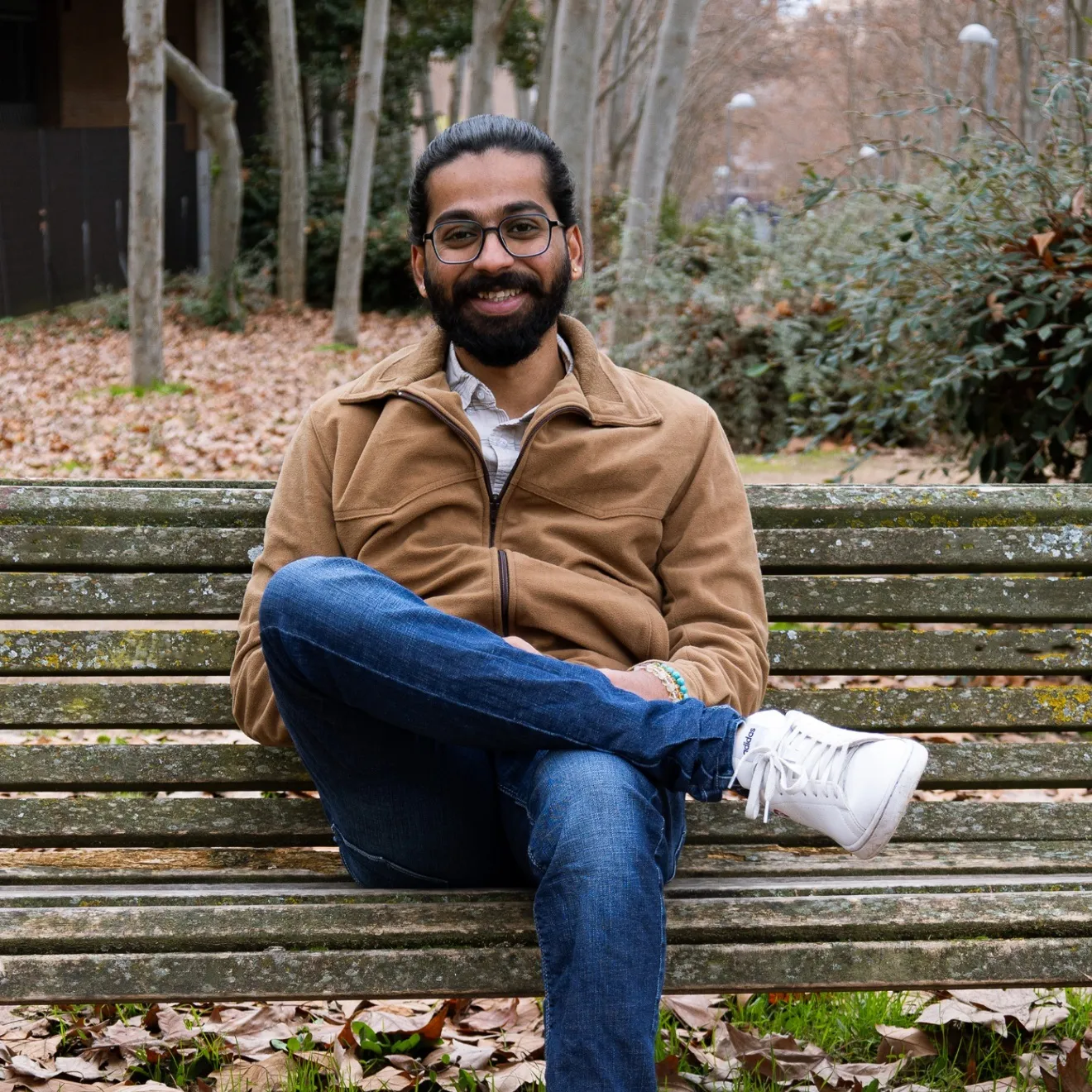 Sanath Kashyap sitting on a park bench outdoors in Madrid
